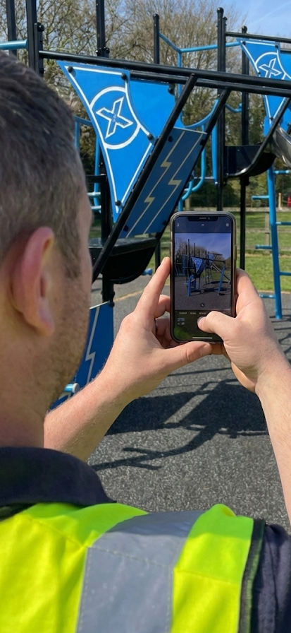 Grounds worker photographing a climbing frame with a smartphone